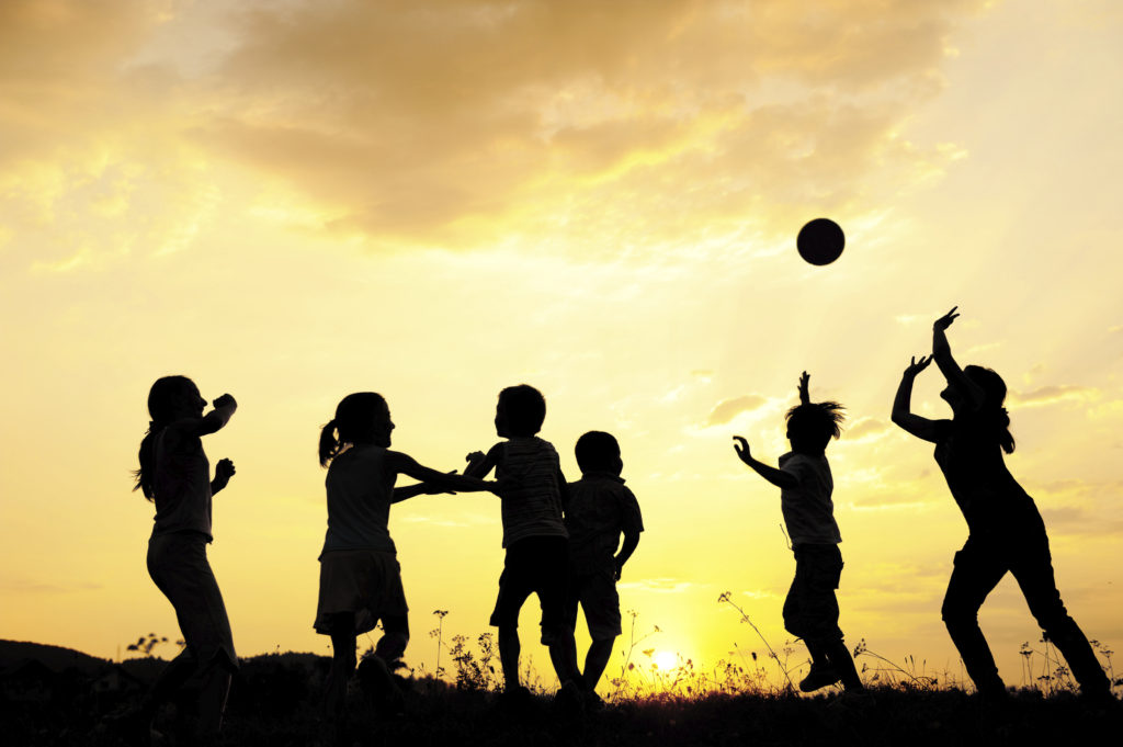 Silhouette, group of happy children playing on meadow, sunset, summertime