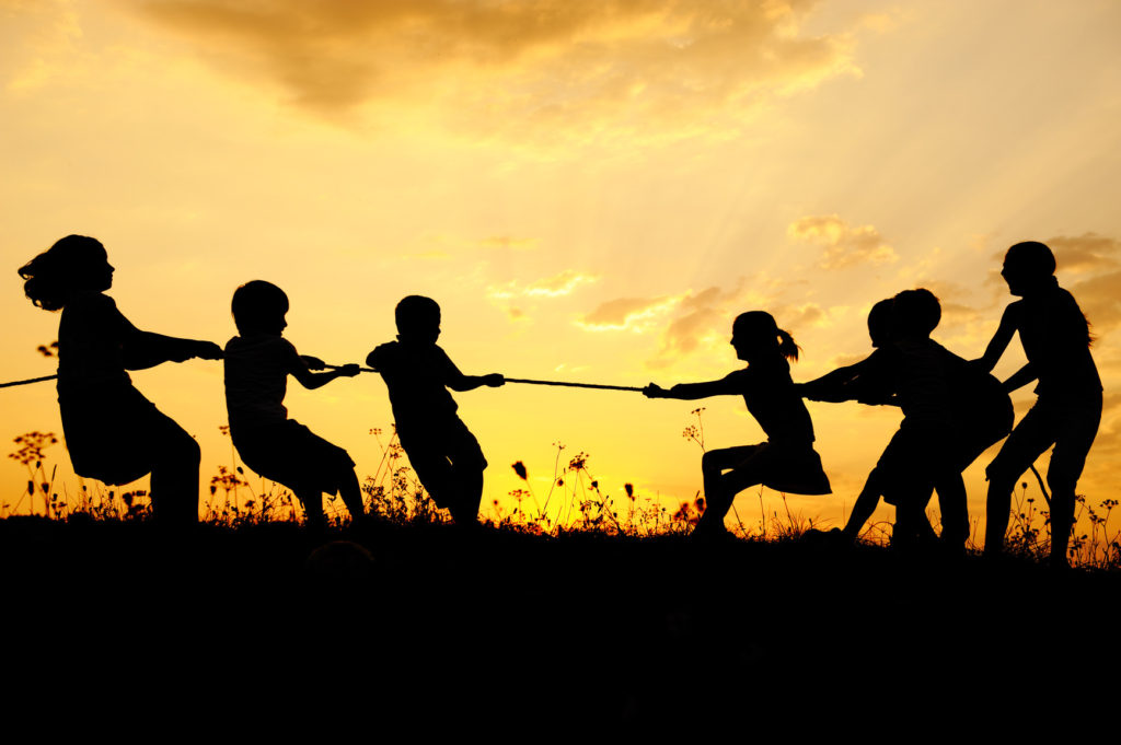 Silhouette, group of happy children playing on meadow, sunset, summertime